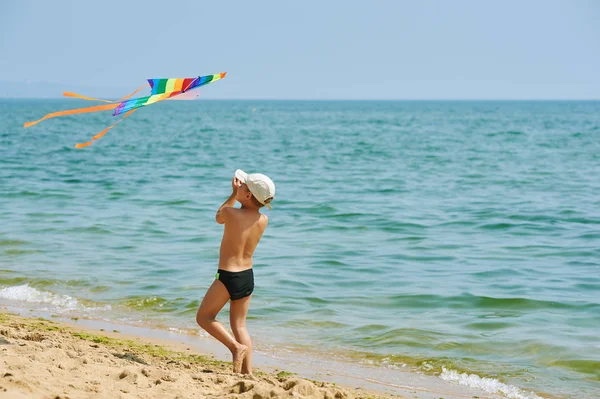 Kleiner Junge ruht sich aus und spielt am Strand mit einem Drachen — Stockfoto