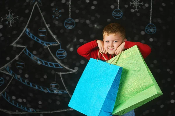 Handsome boy with packages on a dark background . A good purchase — Stock Photo, Image