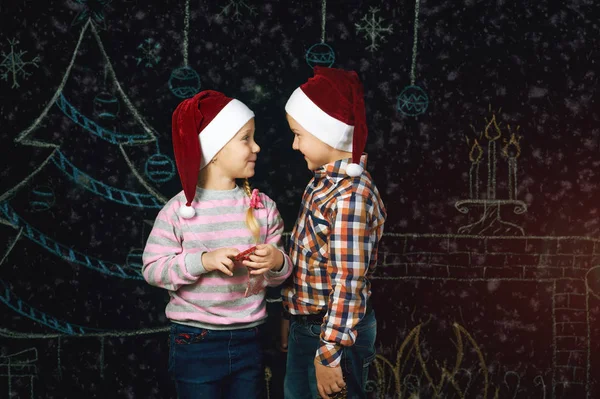 Menino e menina no fundo de Natal, Chapéus de Papai Noel  . — Fotografia de Stock