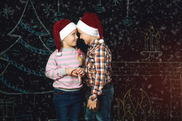 Menino e menina no fundo de Natal, Chapéus de Papai Noel  . — Fotografia de Stock