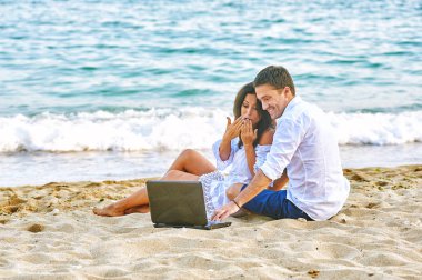 Güzel Romantik Çift sahilde. Seyahat ederken dizüstü resimleri izliyor