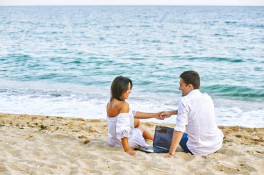 Güzel Romantik Çift sahilde. Seyahat ederken dizüstü resimleri izliyor