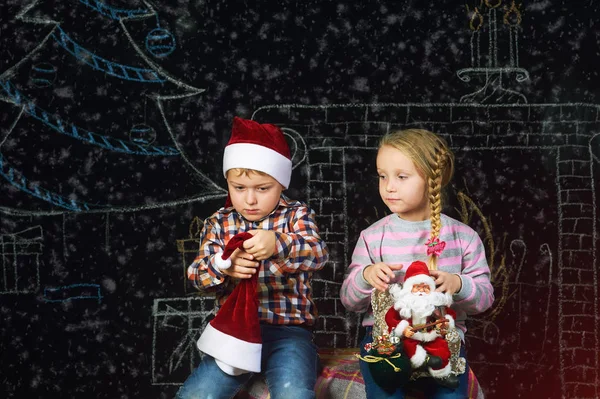 Хлопчик і дівчинка на різдвяному тлі, Санта-капелюхи  . — стокове фото