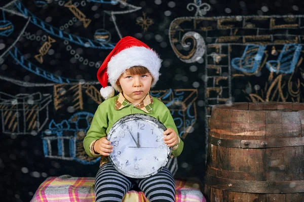 Αγόρι ποζάρει με ένα ρολόι σε Χριστουγεννιάτικο φόντο. Χριστούγεννα του χρόνου — Φωτογραφία Αρχείου