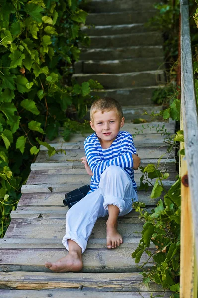 아름 다운 소년 나무 계단에 포즈입니다. 항해 스타일 옷을 입고 . — 스톡 사진