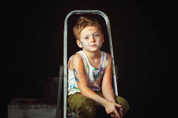 Niño cansado cubierto de pintura sobre un fondo oscuro —  Fotos de Stock