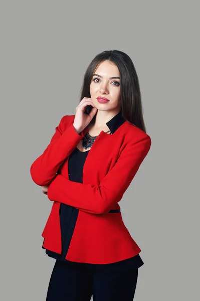 Портрет молодой женщины в красном костюме на сером фоне — стоковое фото