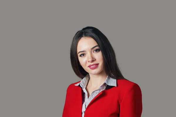 Portréja egy fiatal nő, egy piros öltönyt, egy szürke háttér — Stock Fotó