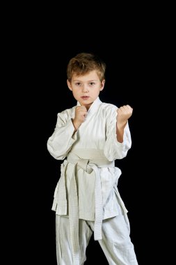 Kimono genç çocuk dövüş sanatları bir siyah arka plan üzerinde gösterir.