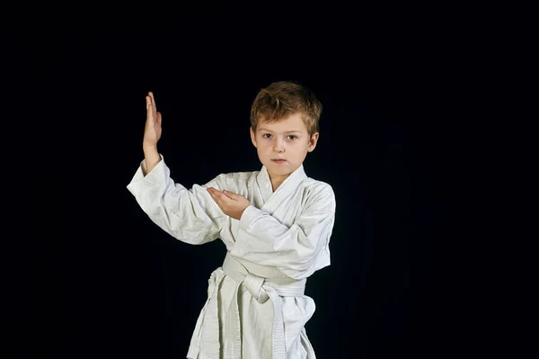 Jovem em quimono mostra as artes marciais em um fundo preto — Fotografia de Stock