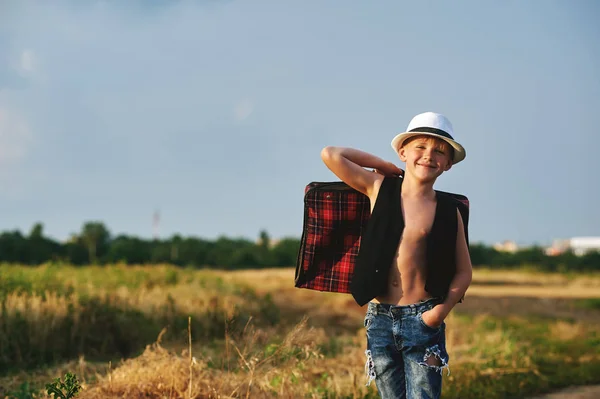 Menino elegantemente vestido no campo com mala — Fotografia de Stock