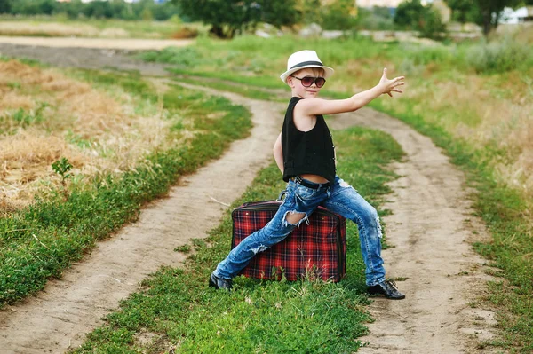 Stilvoll gekleideter Junge im Feld mit Koffer — Stockfoto