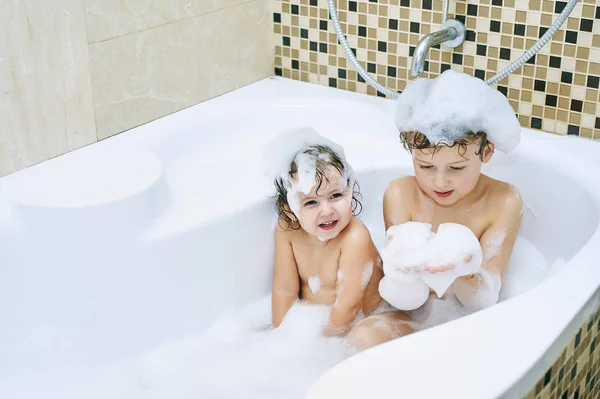 Fröhliche Kinder, die im Badezimmer spielen. Bruder und Schwester genießen Wasserbehandlungen — Stockfoto
