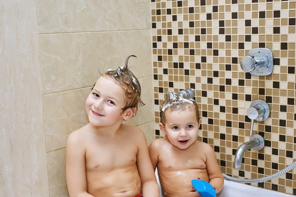 Vrolijke kinderen spelen in de badkamer. Broer en zus genieten van water procedures — Stockfoto