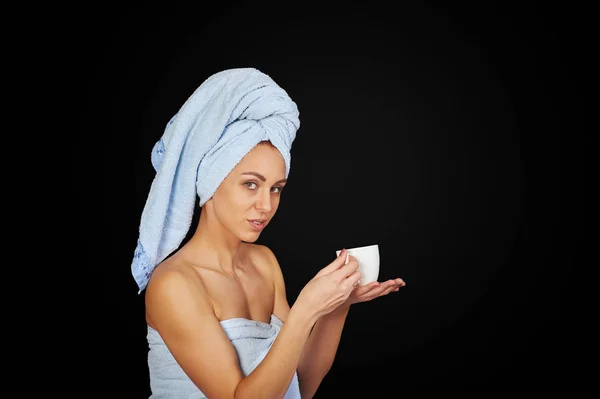 Chica en una toalla con una taza sobre un fondo oscuro —  Fotos de Stock