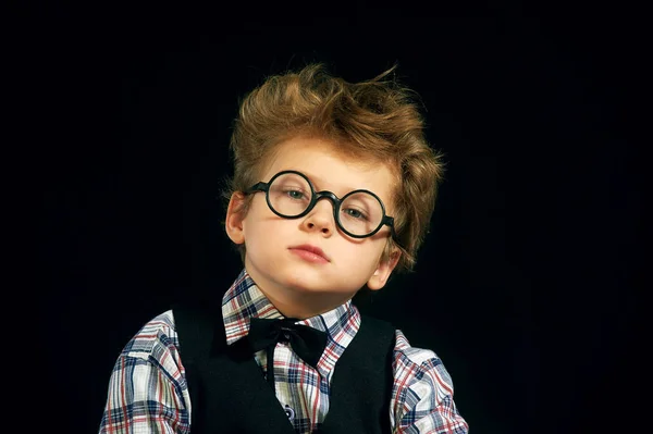 一个男孩戴着眼镜在深色背景上的肖像 — 图库照片