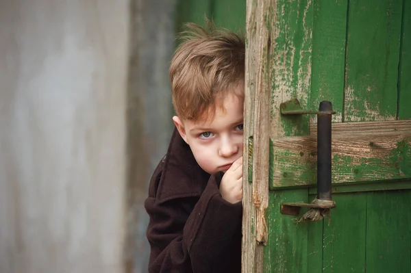Портрет грустного мальчика за дверью — стоковое фото