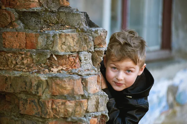 Un chico mira desde detrás de una esquina. Juegos para niños —  Fotos de Stock