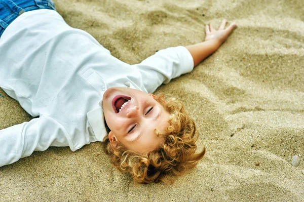 Un ragazzino che gioca sulla riva del mare. Il concetto di svago dei bambini — Foto Stock