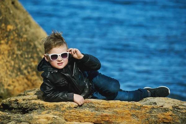 Der Junge in der Brille auf dem Meer. ein Kind posiert im Frühling liegend auf dem Stein auf Meeresgrund — Stockfoto