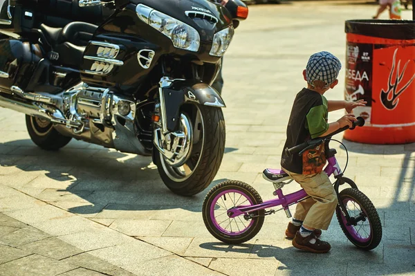 The opening Moto of the season .Odessa 28.05.2016. a boy on a Bicycle enthusiastically looking at the bike — Stock Photo, Image