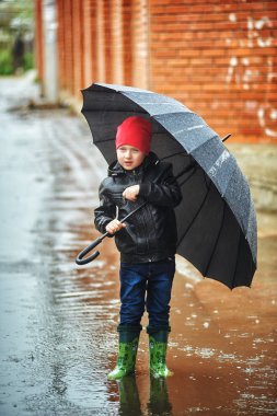 Yağmurda yürümek bahar şemsiye tutan çocuk