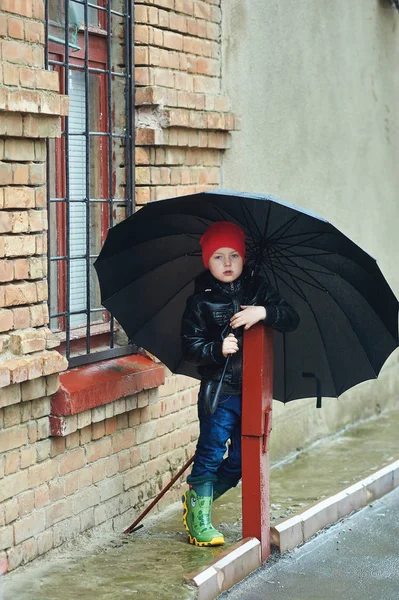 春の雨の中歩いて傘を保持している少年 — ストック写真