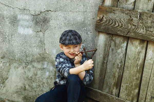 The little boy in the cap , the bully with a slingshot in the hands — Stock Photo, Image