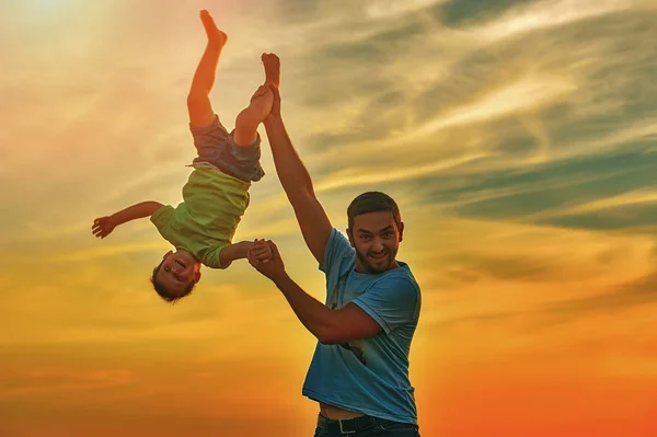 Père heureux jouant avec son fils sur fond de coucher de soleil.Le concept de la fête des pères — Photo