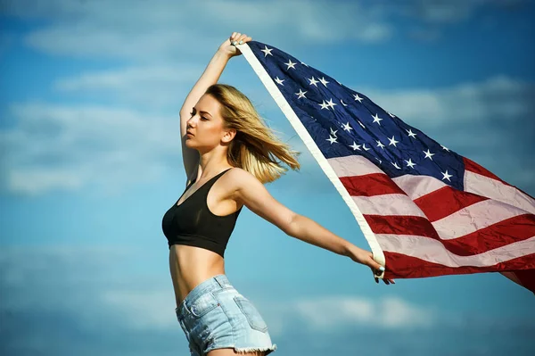 Chica con ondear bandera de EE.UU. en el fondo del cielo azul  . — Foto de Stock