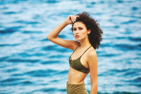 Model poseren tegen de zee in een zwempak, de jonge vrouw die rusten op de zee — Stockfoto