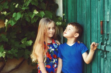 Güzel, zarif şekilde giyinmiş çocuk eski bir vintage kapıda. Çocuk dostluk kavramı