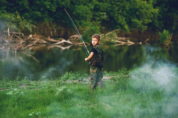Мальчик ловит рыбу в реке. Концепция туризма и отдыха — стоковое фото