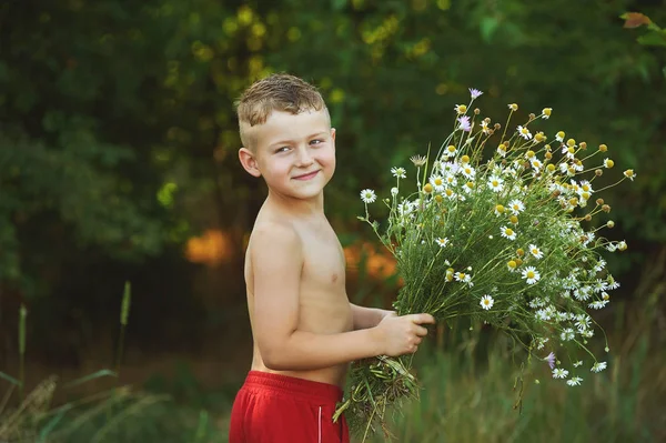 Retrato de niño alegre en la naturaleza con un ramo de flores silvestres —  Fotos de Stock