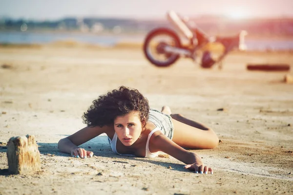 Meisje op de grond liggen. Op de achtergrond een gebroken motorfiets . — Stockfoto