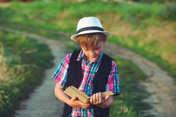 フィールドで本を読んでいる少年。子供の教育の概念 — ストック写真