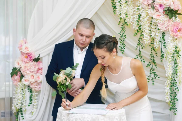 Cerimônia de casamento. A noiva e o noivo, deixando suas assinaturas — Fotografia de Stock