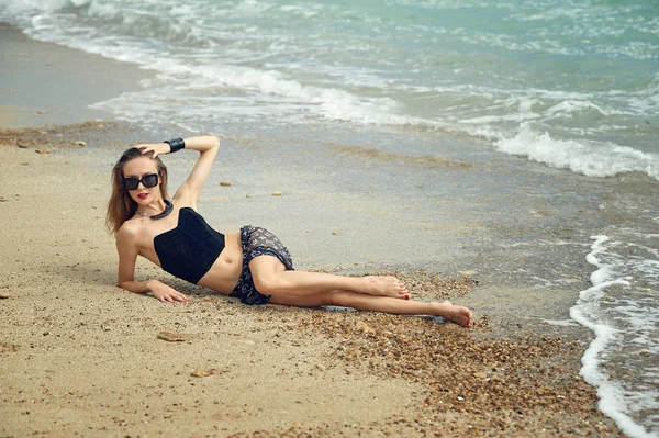 Jonge vrouw aan het strand aan de kust — Stockfoto