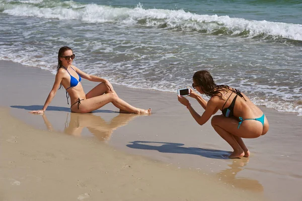 Eğlenceli deniz kenarında iki genç kadın, o onun kız arkadaşı bir cep telefonu alır