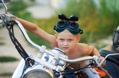 çocuk babasının motosiklet üzerinde oturur. Bir motorcu olma hayali