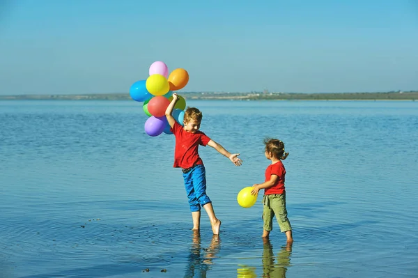 Niedlichen Jungen und Mädchen spielen mit bunten Luftballons im Freien. — Stockfoto