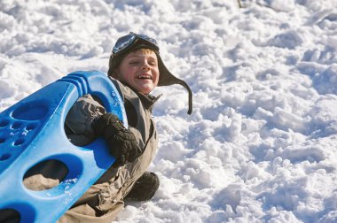 Bir soğuk kış günü, kızağı tutan parkta bir yürüyüş çocuk. Kış aktif tatili