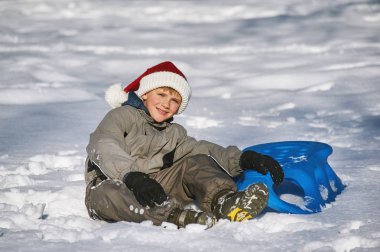 Bir soğuk kış günü, kızağı tutan parkta bir yürüyüş çocuk. Kış aktif tatili