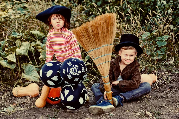 Μικρό κορίτσι με τον αδελφό του στο κοστούμι καπέλα σε εξωτερικούς χώρους με κολοκύθες. Χαρούμενο χελοουγουίν ! — Φωτογραφία Αρχείου