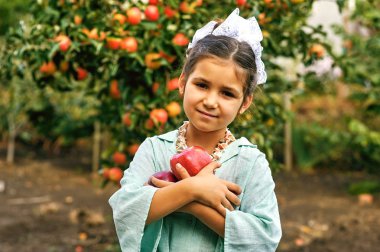 Çocuklar sonbaharda elma toplamak. Bir sepet elma tutan kız