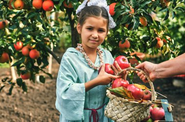 Çocuklar sonbaharda elma toplamak. Bir sepet elma tutan kız