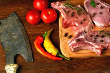 Çiğ biftek, pirzola, et baharatlar ve sebzeler üzerinde ahşap masa