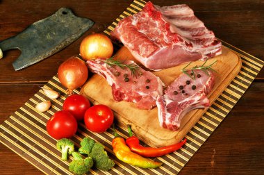 Çiğ biftek, pirzola, et baharatlar ve sebzeler üzerinde ahşap masa