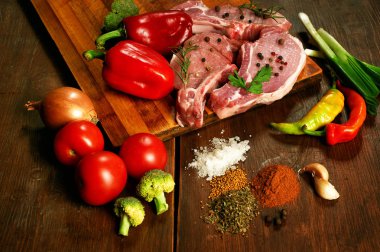 Çiğ biftek, pirzola, et baharatlar ve sebzeler üzerinde ahşap masa