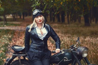 Park sonbaharda eski bir motosiklet üzerinde çekici kız